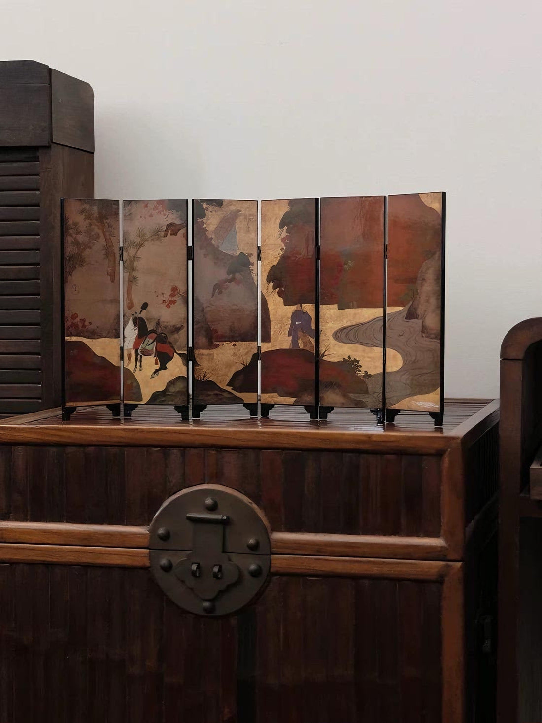 Decorative Japanese folding screen with samurai artwork displayed on a wooden chest