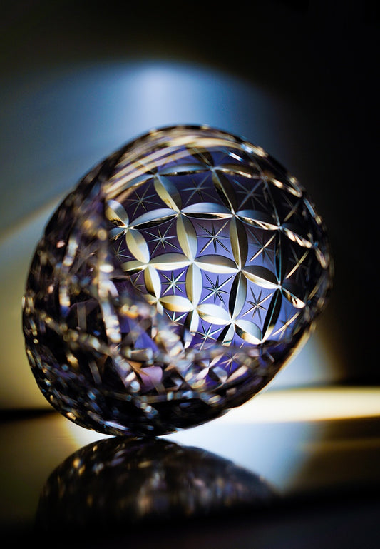 Rin Essense whiskey glass ornate cut crystal tumbler with geometric star pattern tilted on reflective surface