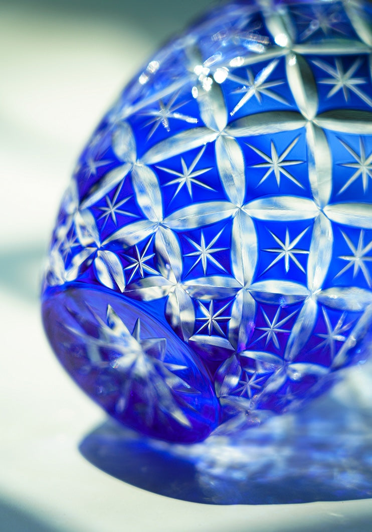 Blue cut crystal whiskey glass with starburst pattern close up decorative tumbler lying on side