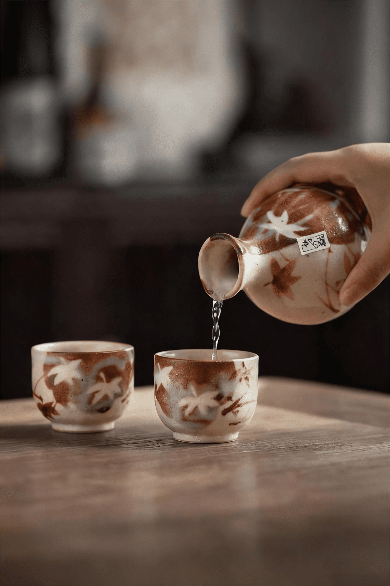 Rin Essense sake cup set with autumn leaf design and hand pouring sake into cup