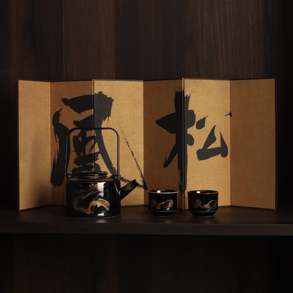 Rin Essense black lacquer teapot and two cups with gold motifs displayed before a washi shoji folding screen