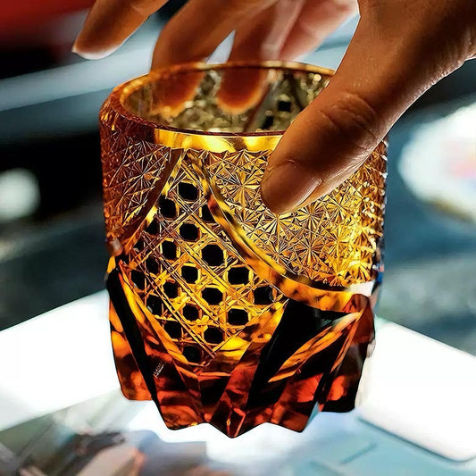 Rin Essense Satsuma Kiriko whiskey glass amber cut crystal tumbler held by hand showing intricate geometric patterns