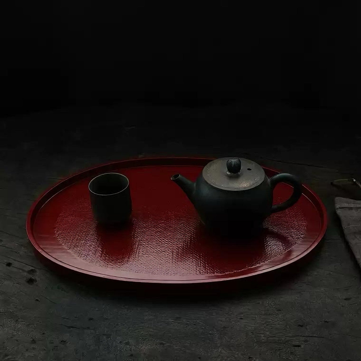 Rin Essense red oval tea tray with a black teapot and matching cup on a dark surface