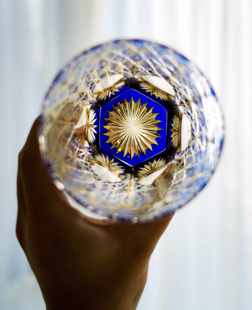 Edo Kiriko whisky glass blue and gold cut crystal held by hand showing intricate starburst cuts