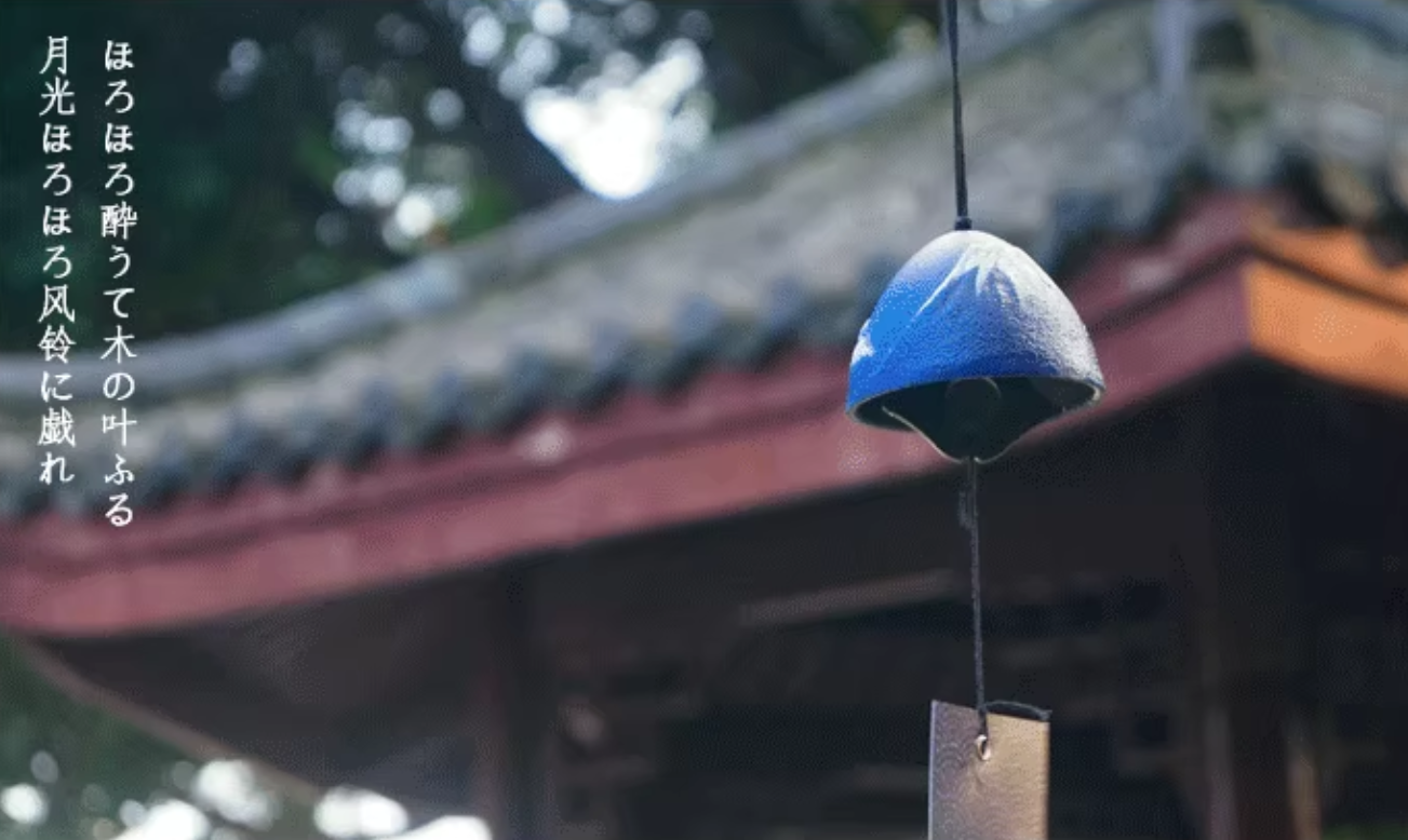 Rin Essense blue ceramic Japanese wind chime furin hanging in a temple garden with wooden clapper tag