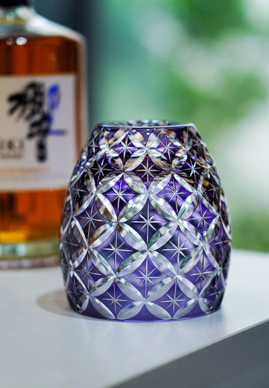 Rin Essense purple cut crystal whiskey glass with intricate star and lattice pattern on white surface