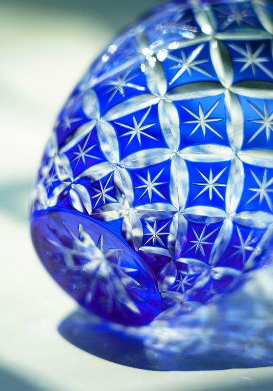 Blue cut crystal whiskey glass with starburst pattern close up decorative tumbler lying on side
