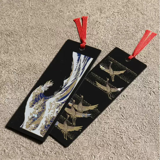 Two black Japanese style handcrafted lacquerware bookmarks with red tassels featuring gold cranes and blue wave design