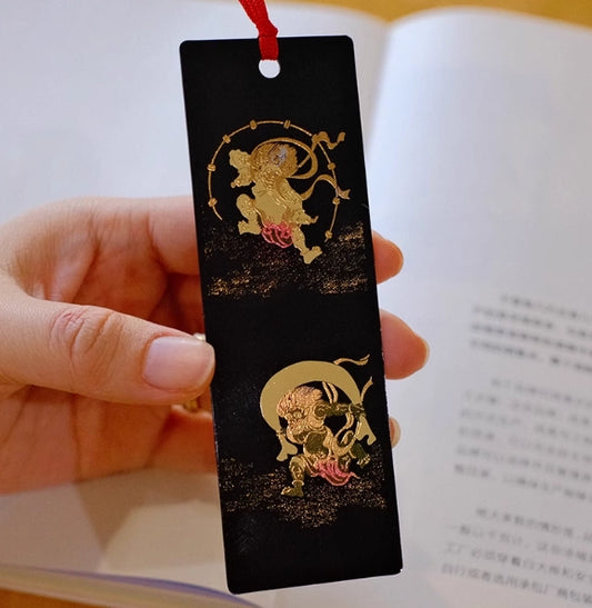 Rin Essense handcrafted lacquerware bookmarks black bookmark with gold mythical motifs and red tassel held over open book