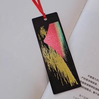handcrafted lacquerware bookmarks black rectangular bookmark with gold brushstrokes pink green mountain and red ribbon on open book