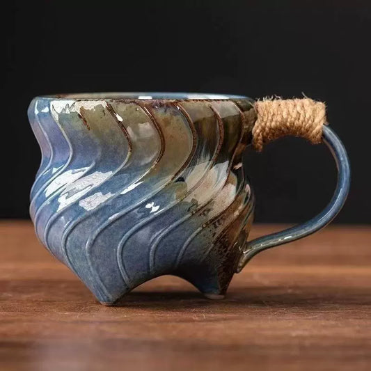 handmade stoneware coffee mug blue green spiral glaze with twine wrapped handle and tripod feet