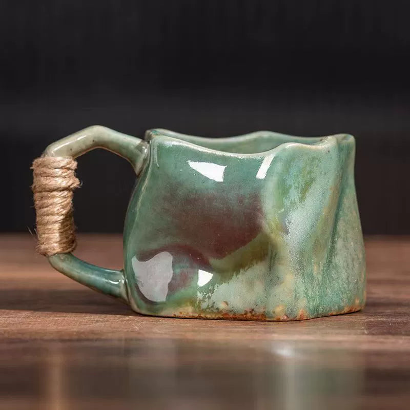Rin Essense handmade stoneware coffee mug in green glossy glaze with irregular shape and twine wrapped handle