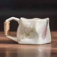 Rin Essense handmade stoneware coffee mug with irregular hand formed shape soft green and pink glaze and twine wrapped handle