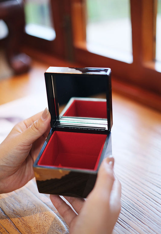 Rin Essense Japanese lacquerware jewelry box open showing red interior and mirror held in hands over wooden table
