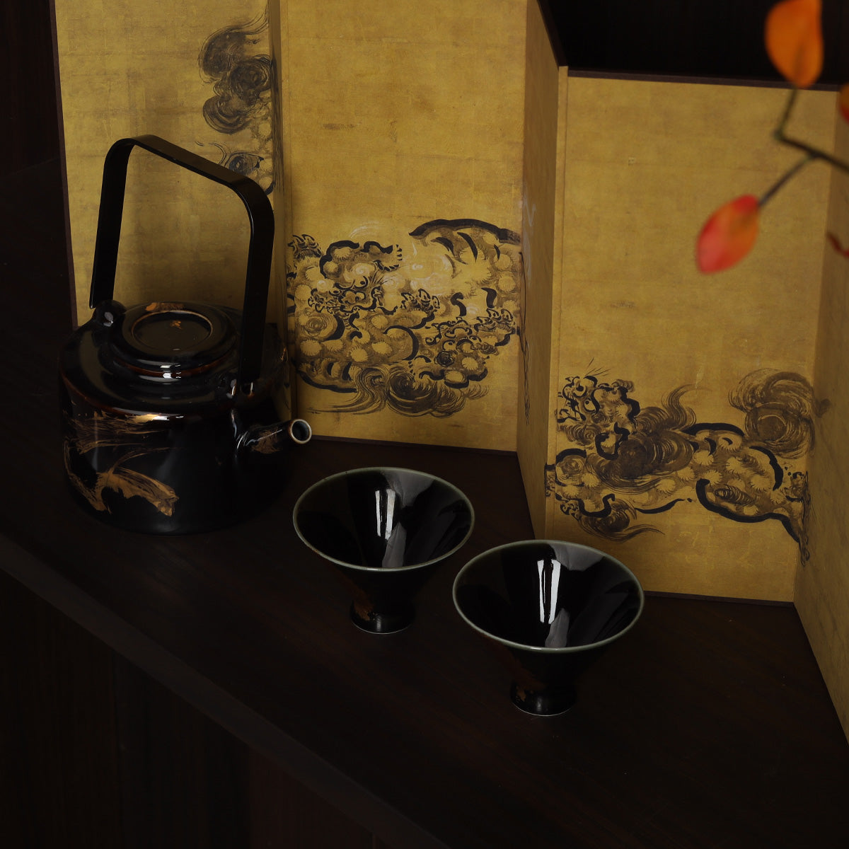 Washi shoji folding screen with gold ink cloud panels beside black lacquer teapot and two cups