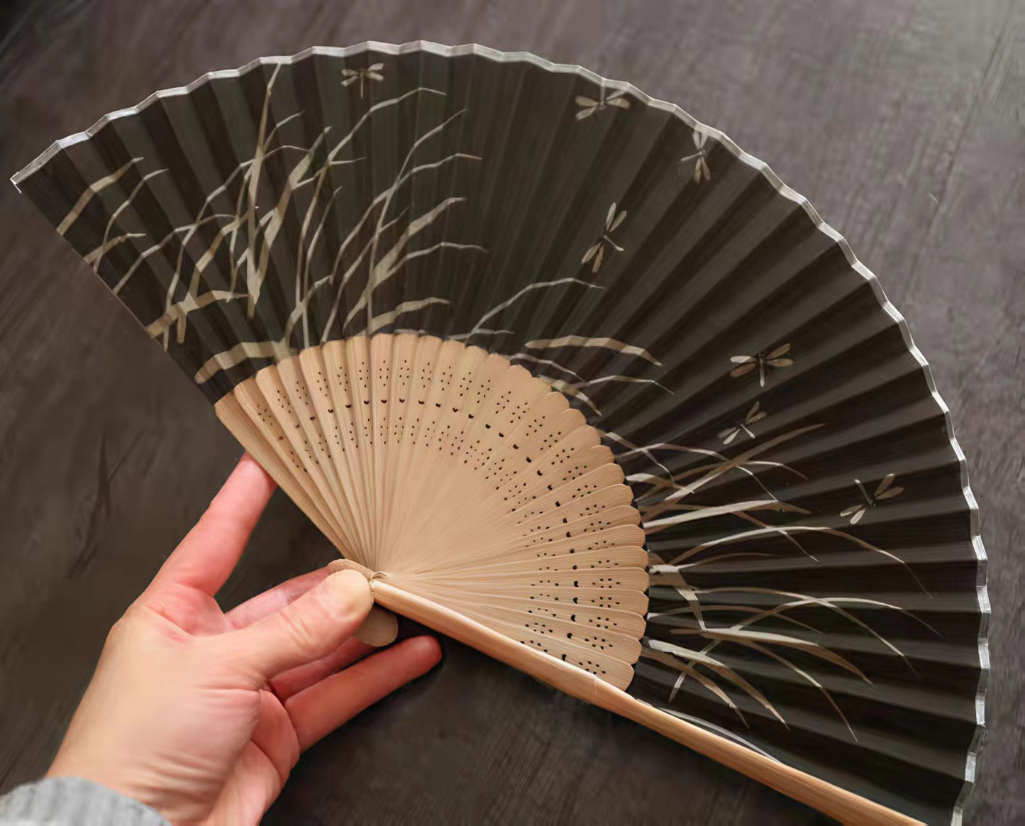 Hand holding a traditional Japanese folding fan with black and beige design artistic Japanese gifts US shipping