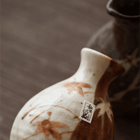 Rin Essense ceramic sake cup with brown and white leaf design on wooden surface