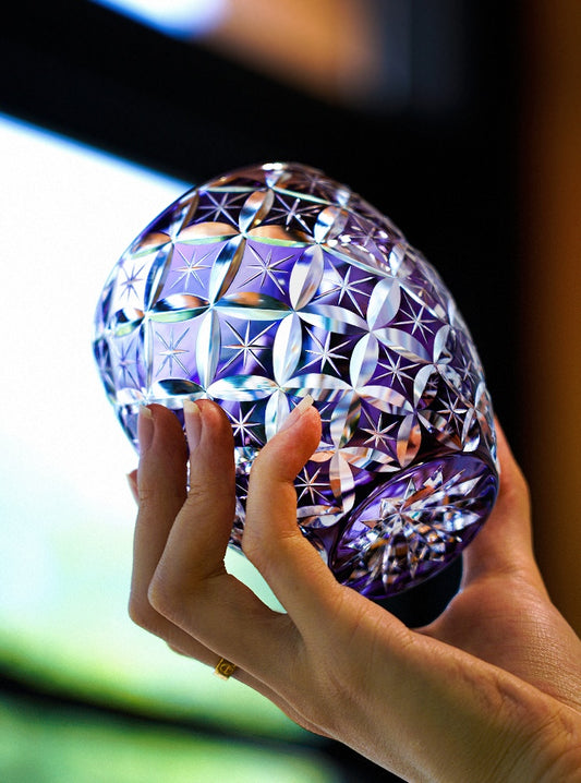 Rin Essense cut crystal whiskey glass in purple with intricate starburst cut pattern held in hand