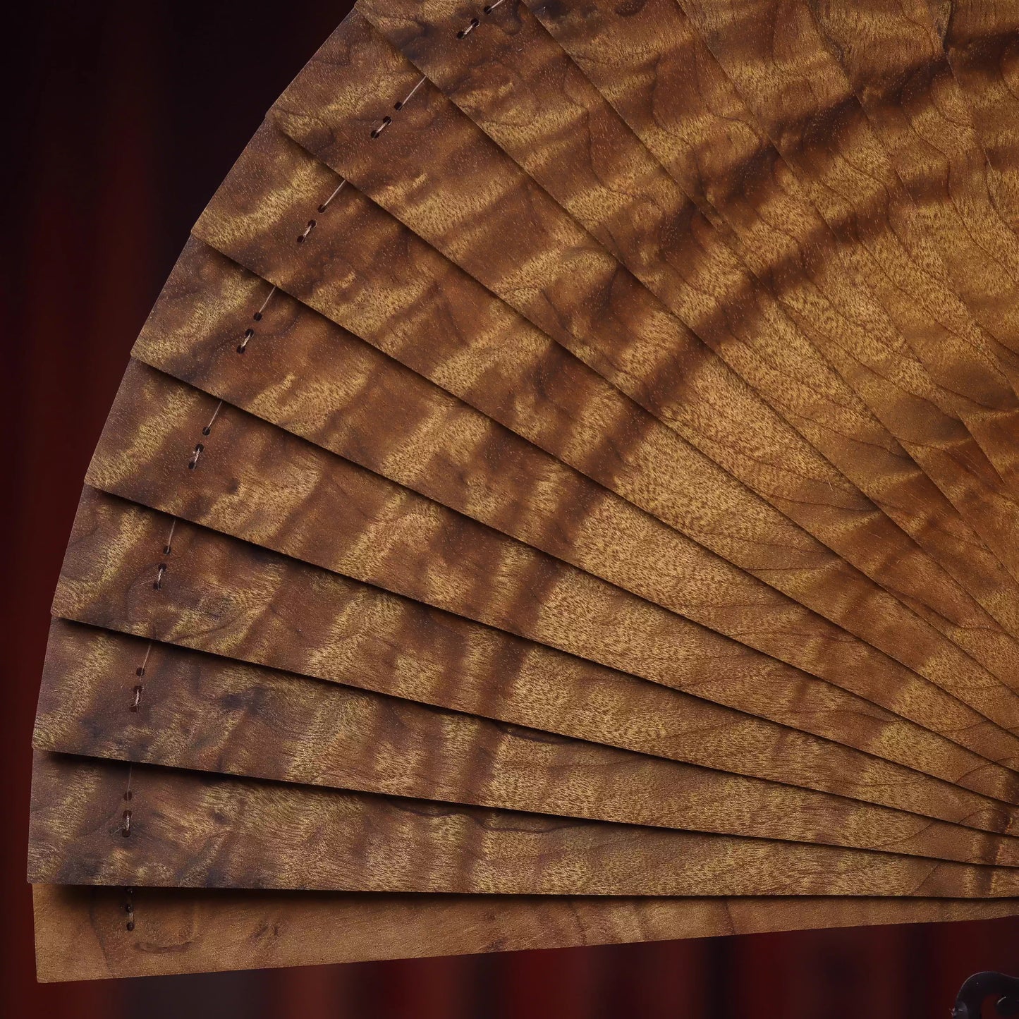 Close-up of a golden nanmu wood folding fan showcasing its detailed grain and smooth finish