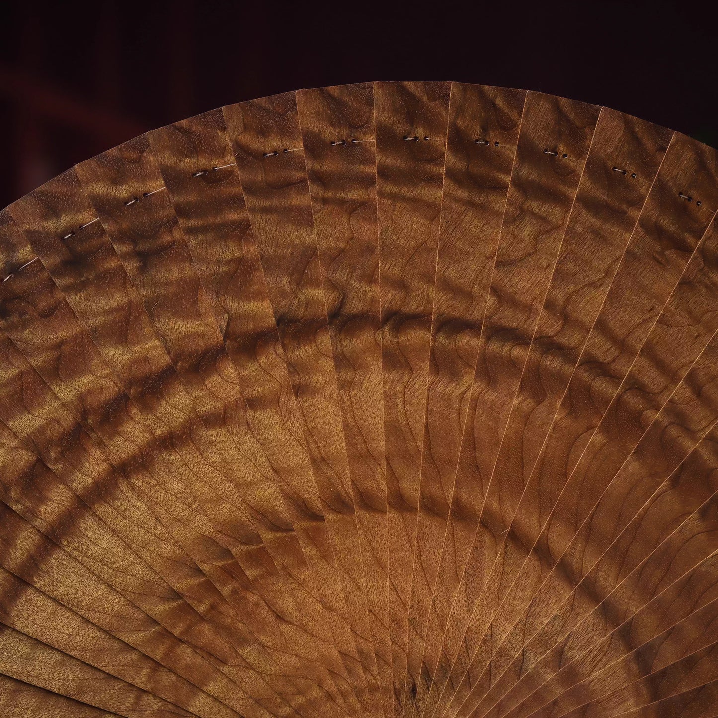 Close-up of golden nanmu wood folding fan showing detailed wood grain pattern and craftsmanship