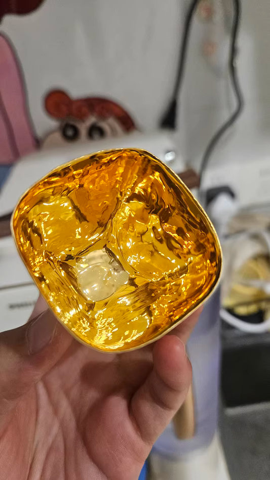 Close-up of hand-shaped gilded Japanese cup showing shiny gold interior held in hand