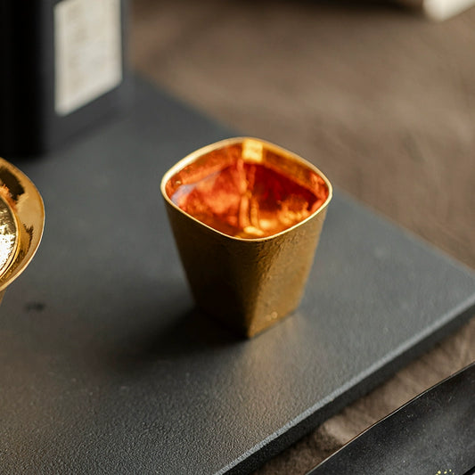 Hand-shaped gilded Japanese cup with textured gold finish by Rin Essense on black surface