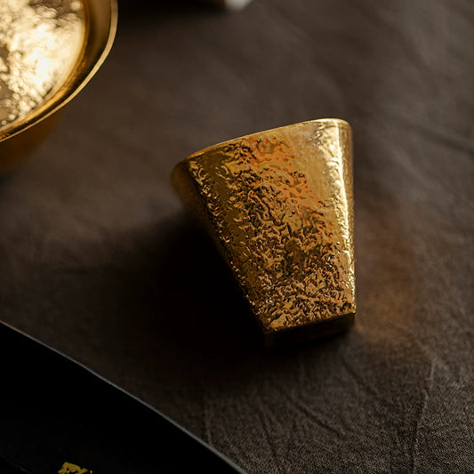 Hand-shaped gilded Japanese cup with textured gold finish on dark fabric surface