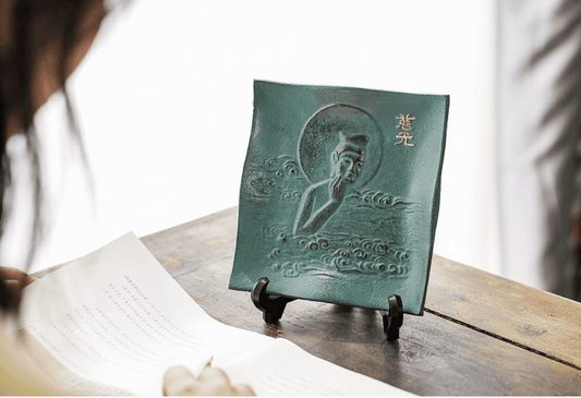 Japanese ironware plate for display home decor featuring a green square design with a carved figure and gold accents on a wooden stand