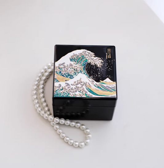 Rin Essense black lacquer jewelry box featuring a detailed wave design with a pearl necklace beside it