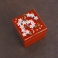 Rin Essense red jewelry box with white floral design on top placed on brown surface