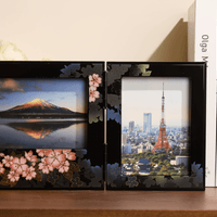 Rin Essense decorative black photo frame with floral design holding two landscape photos on a wooden shelf