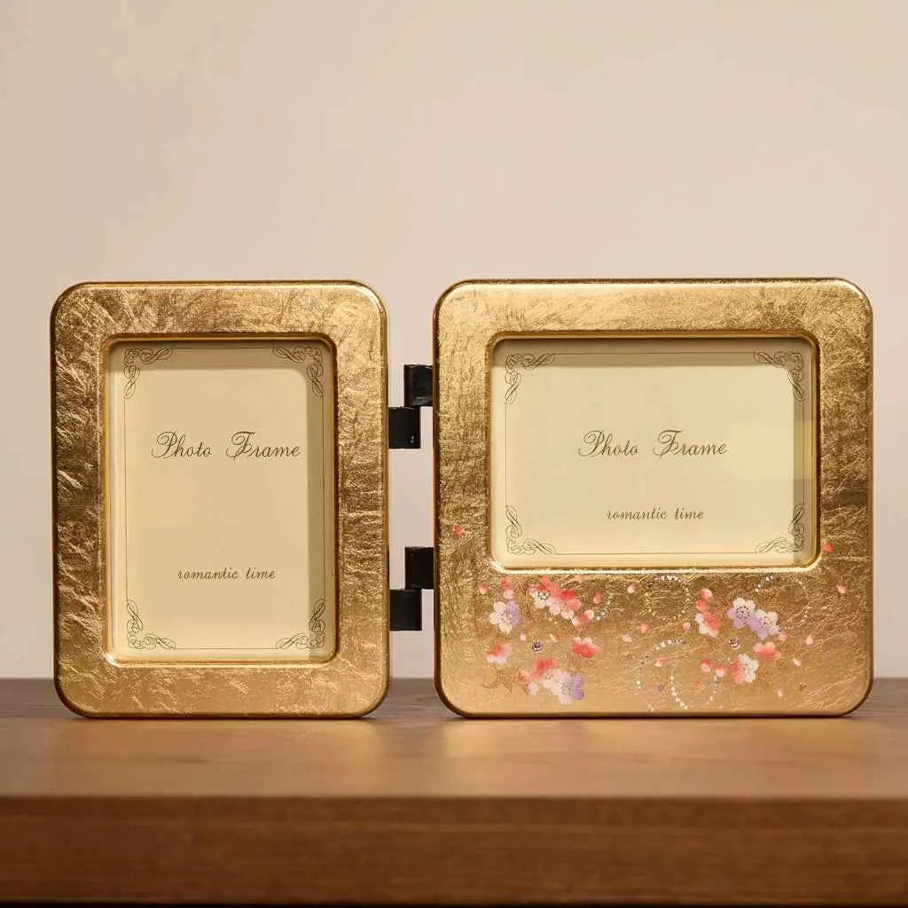 Rin Essense gold-tone double hinged decorative photo frame with floral accents on wooden surface