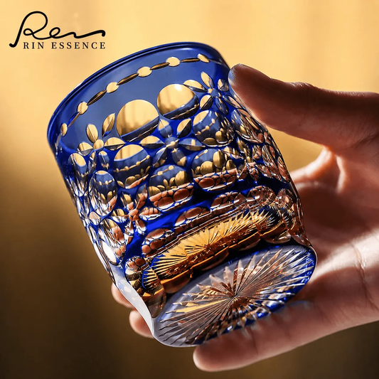 RIN ESSENCE blue and gold ornate glass whiskey held in hand with intricate floral design