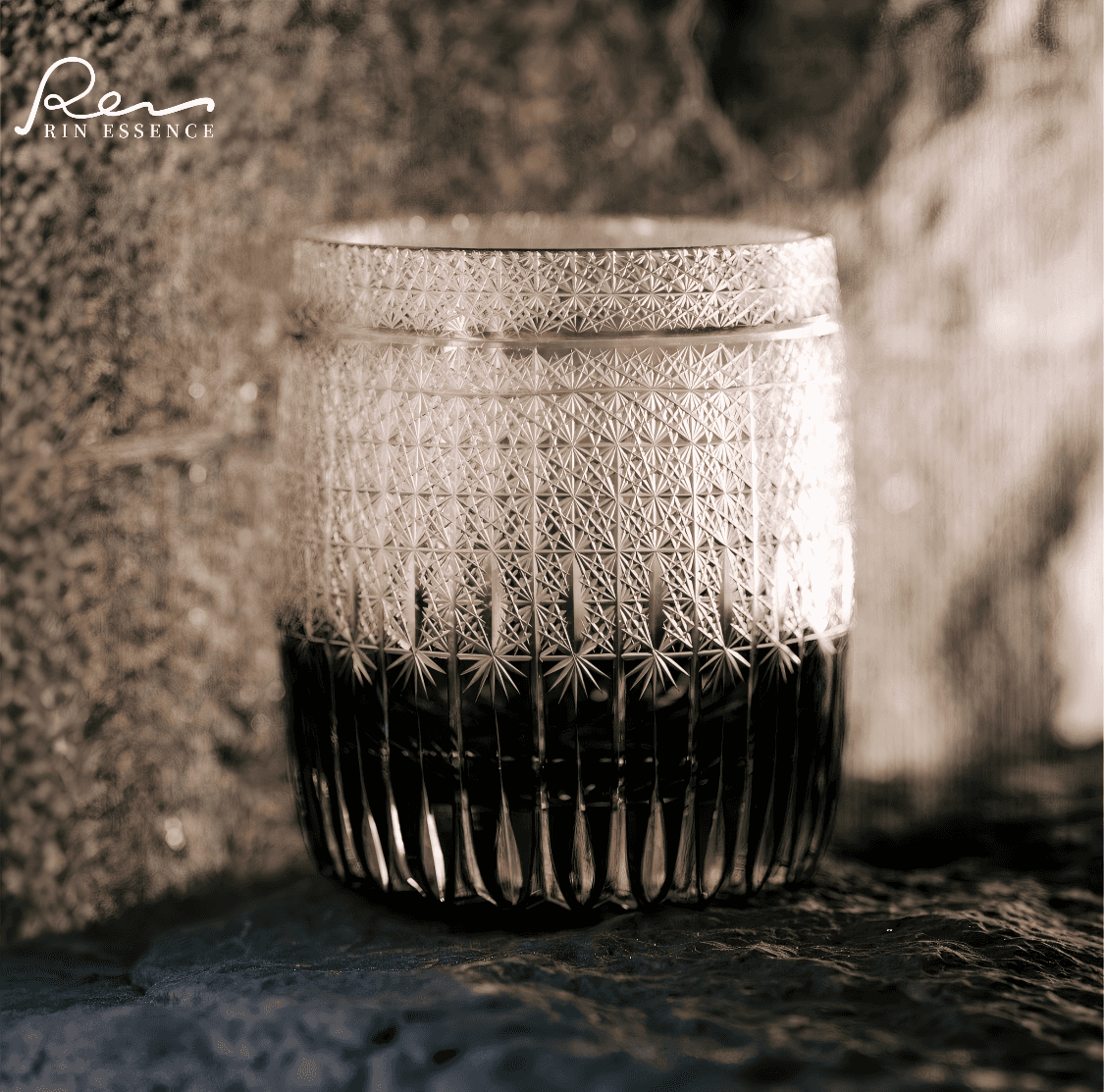 Rin Essense whiskey glass with intricate cut pattern and dark liquid inside showcasing whiskey with glass