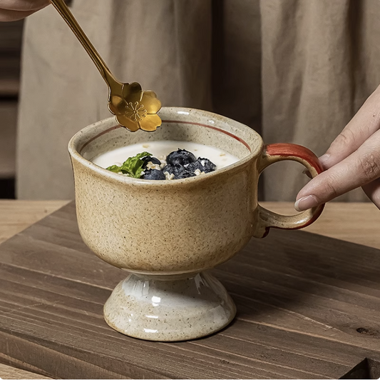 Japanese vintage ceramic cup footed beige speckled mug with red trimmed handle filled with yogurt and blueberries