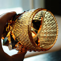 Handheld Rin Essense Satsuma Kiriko whiskey glass in amber cut crystal showing intricate geometric facets and shine