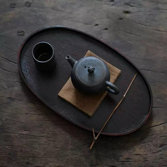 Rin Essense rustic black metal tea tray with teapot cup and wooden stick on textured surface