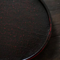 Rin Essense round textured black and red tea tray on wooden surface