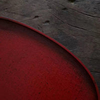 Close-up of a rustic red tea tray with textured surface on a wooden background