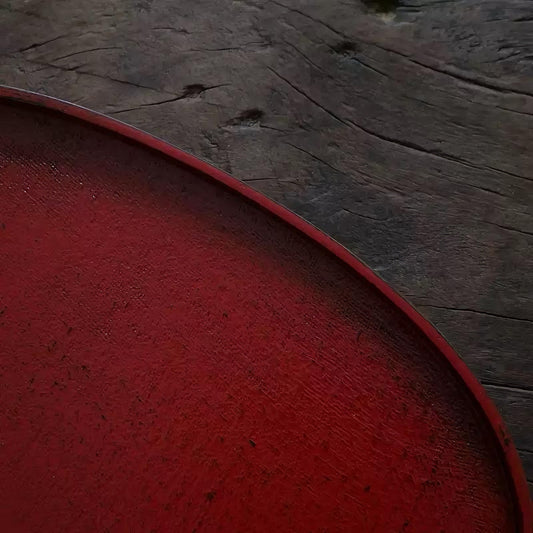Close-up of a rustic red tea tray with textured surface on a wooden background