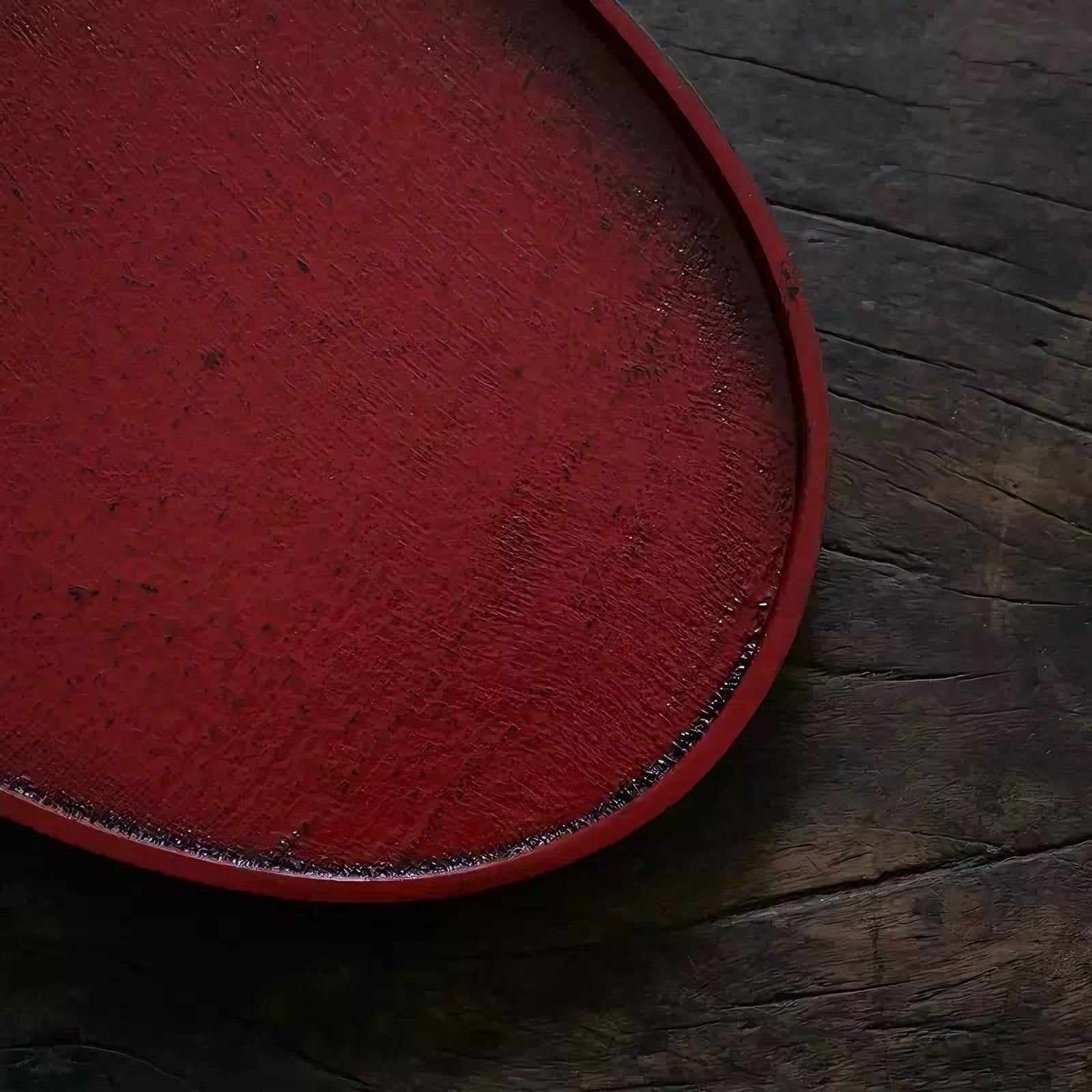 Rin Essense red round tea tray with textured surface on dark wooden background