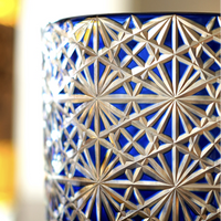 Close up of Rin Essense Edo Kiriko whisky glass in cobalt blue with intricate starburst cut pattern and amber background