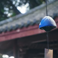 Rin Essense blue ceramic Japanese wind chime furin hanging in a temple garden with wooden clapper tag
