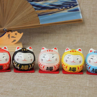 Five colorful ceramic cat daruma tumbling doll ornament figurines in red black white yellow and blue