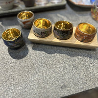 Rin Essense traditional Japanese ceramic drinkware sake cups with gold interior and decorative exteriors on a wooden tray