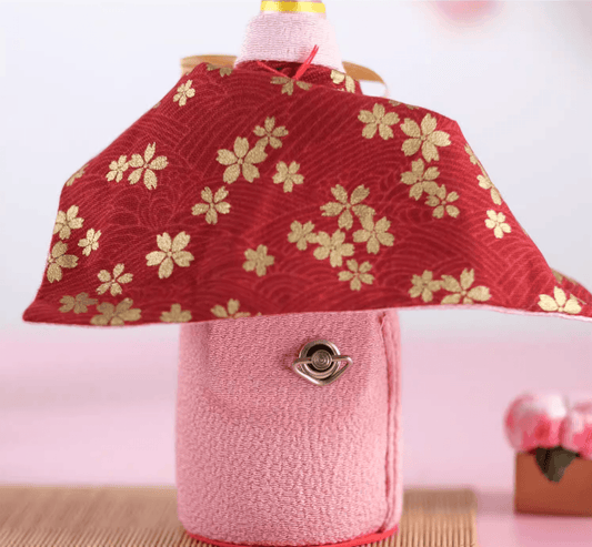 Rin Essense decorative bottle cover in pink with red and gold floral patterned fabric cape