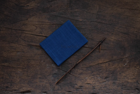 Japanese Indigo Tea Cloth – Hand-Dyed Cotton Linen folded on rustic wooden surface with a thin wooden stick