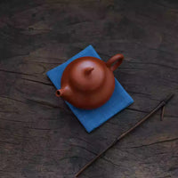 Japanese Indigo Tea Cloth – Hand-Dyed Cotton Linen placed under a traditional brown teapot on wooden surface