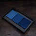 Japanese Indigo Tea Cloth – Hand-Dyed Cotton Linen in three shades of blue folded neatly on a dark wooden tray