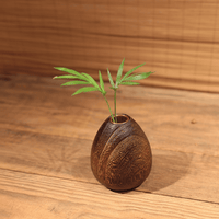 Rin Essense wood vase with natural textured finish holding green leaves on wooden surface